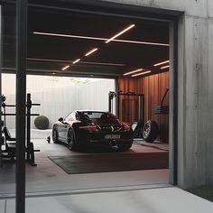 a black sports car parked in a garage next to a weight rack and exercise equipment