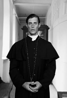 a man wearing a priest's robe and holding a rosary