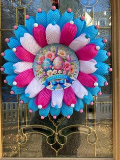 a colorful flower decoration hanging on the front door of a building with gold trimmings