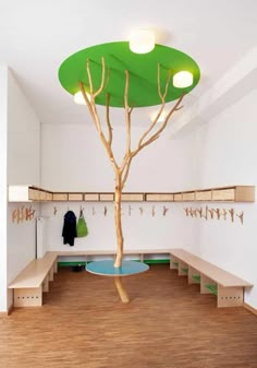 a tree in the middle of a room with benches and coat racks on either side