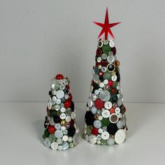 two christmas trees made out of buttons on a white surface with a red star above them