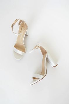 two pairs of white high heeled shoes on top of each other, one with an ankle strap