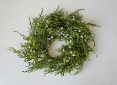 a close up of a wreath on a white surface with green and white flowers in the center