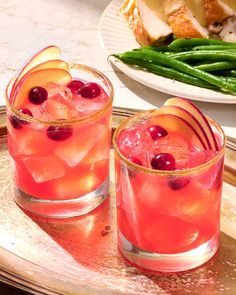 two glasses filled with drinks sitting on top of a metal tray next to green beans