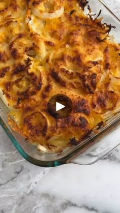 a casserole dish with onions and cheese in it on a marble counter top