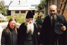 three people standing next to each other in front of a house with a long white beard