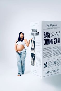 a pregnant woman standing next to a large poster