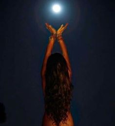 a woman reaching up into the sky at night