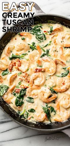 a skillet filled with shrimp and spinach covered in cheese sauce on top of a marble counter