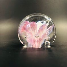 a glass ball with pink and white designs on it sitting on top of a table