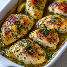 chicken with lemon and herbs in a white casserole dish