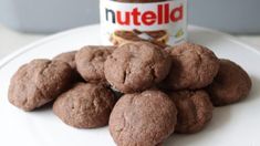 a white plate topped with chocolate cookies next to a jar of nutella