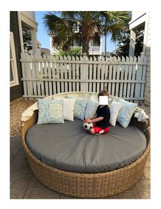 a young boy sitting on top of a round couch with pillows and a stuffed animal