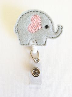 an elephant shaped badge with a pink heart on it's head is attached to a white lanyard