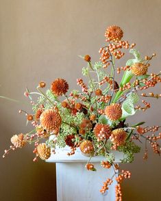 a white vase filled with lots of orange flowers