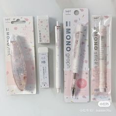 three pens and two erasers sitting on top of each other in front of some packaging