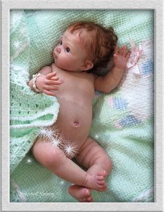 a baby laying on top of a bed under a green blanket with white sparkles