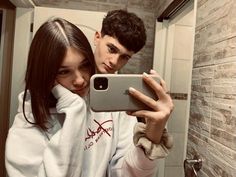 a young man and woman taking a selfie in the bathroom with their cell phone