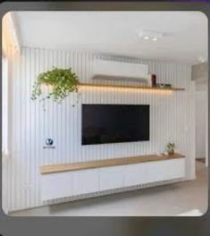 the television is mounted on the wall in the living room with white paneling and wooden shelves