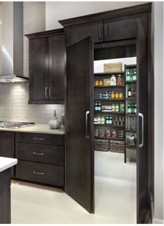 an open pantry in the middle of a kitchen with dark wood cabinets and white counter tops