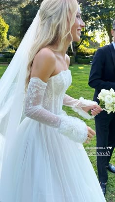 a woman in a white wedding dress is walking next to a man wearing a tuxedo