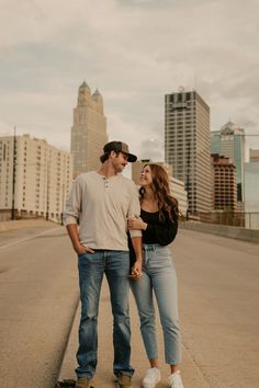 a man and woman standing on the side of a road in front of tall buildings