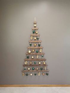 a wooden christmas tree with ornaments hanging from it's sides on a wall in a room