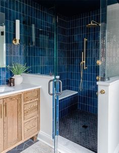 a blue tiled bathroom with wooden cabinets and a shower stall in the corner, next to a sink