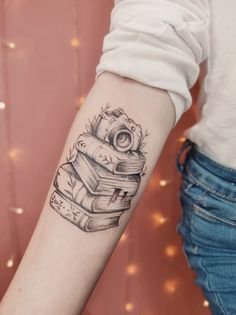 a person with a tattoo on their arm is holding a stack of books and an owl