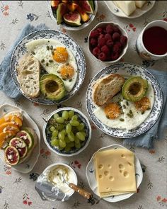 a table topped with plates of food next to bowls of fruit and crackers on top of a table