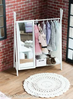 an open white cabinet with clothes hanging on the rack and a round doily rug next to it