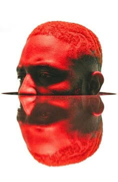 a man's face is reflected in the water with red paint on his face