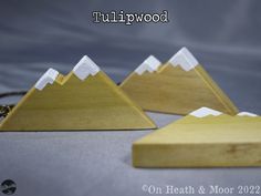 three wooden mountains are shown on a gray surface with the words tullipwood written below them