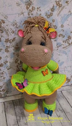 a crocheted stuffed animal wearing a green dress with butterflies on it's head