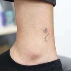 a small dandelion tattoo on the side of a woman's neck is shown