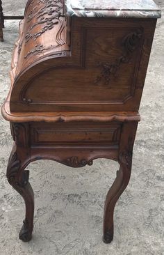 an old wooden desk with marble top sitting on the ground in front of a building