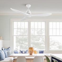 a living room filled with furniture and a white ceiling fan above a dining area table