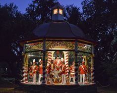 an elaborate carousel with red and white uniforms on it's sides in the evening