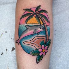 a dolphin and palm tree tattoo on the leg