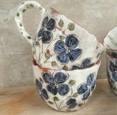 two blue and white flowered cups sitting on top of a wooden table