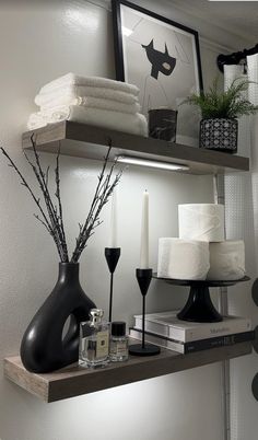 a shelf with candles, towels and other items on it in a room that has white walls