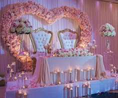 a table with candles and flowers on it in front of a heart - shaped mirror