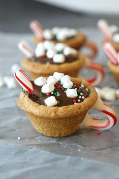 small cupcakes with candy canes and marshmallows in them on a table