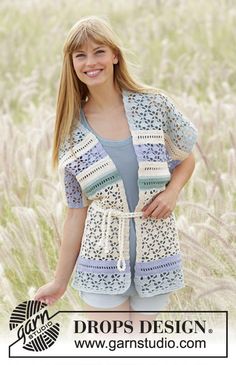 a woman standing in a field wearing a crochet cardigan