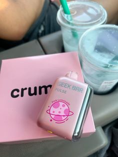 a pink phone case sitting on top of a table next to a cup and drink