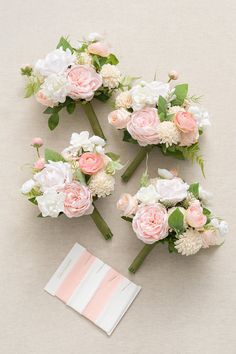 three bouquets of pink and white flowers are laid out on the floor next to each other