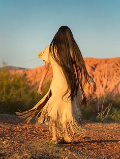 a woman with long hair walking in the desert