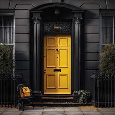 a yellow door and chair in front of a black house