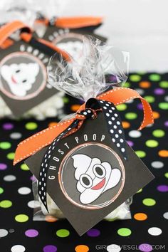 two halloween treat bags sitting on top of a polka dot tablecloth with an orange ribbon