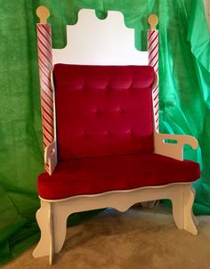 a red and white chair sitting in front of a green curtain with candy canes on it